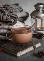 Still life details, stack of winter sweaters, cup of hot chocolate, vintage notebook and cone on gray wall background