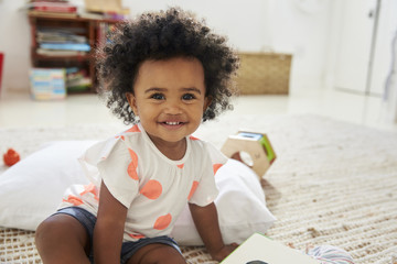 Portrait Of Happy Baby Girl Playing With Toys In Playroom - obrazy, fototapety, plakaty