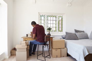 Man In Bedroom Running Business From Home Labeling Goods