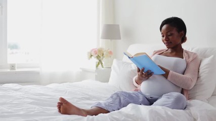 happy pregnant african woman reading book at home - Powered by Adobe
