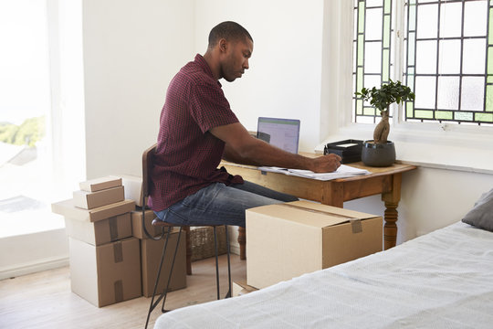 Man In Bedroom Running Business From Home Labeling Goods