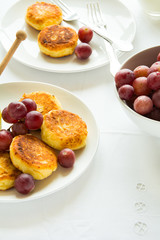 Breakfast with mini cheesecakes, grapes, cream and honey on a white plate