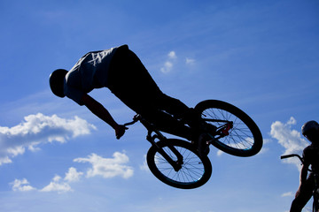 Fototapeta na wymiar Bikers jumping on a ramp in the park