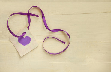 Valentine's day concept. Purple heart shape with ribbon on a light wooden background. Copyspace