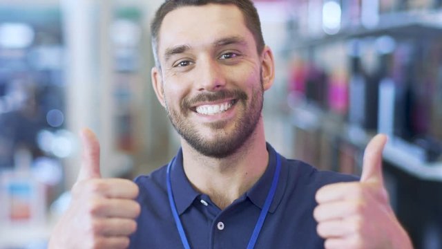 Portrait of a Professional Consultant Smiling and Giving Thumbs Up in the Bright, Modern Electronics Store.The Depth of Field Shot. Shot on RED EPIC-W 8K Helium Cinema Camera.