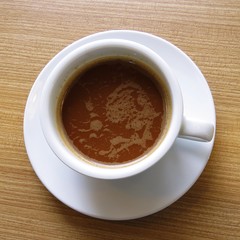 Top view of white coffee cup on a wooden table.