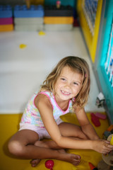 Little girl in playground. Caucasian girl playing with toy. Looking at camera.