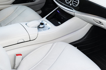 White leather interior of the luxury modern car. Leather comfortable white seats and multimedia. Steering wheel and dashboard. Automatic gear shift. Car interior details