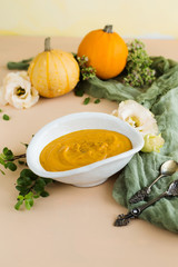 Soup-puree of pumpkin in a white plate on brown background