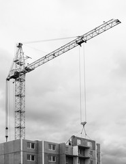 Construction site. Construction cranes and apartment building under construction against blue sky. Concept of construction industry, mortgage, estate, engineering, business, building and architecture