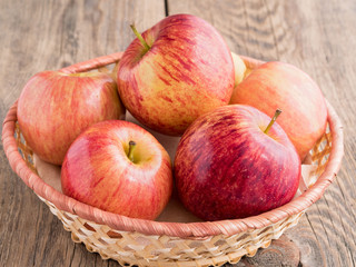 ripe juicy red apples in a basket on a wooden table