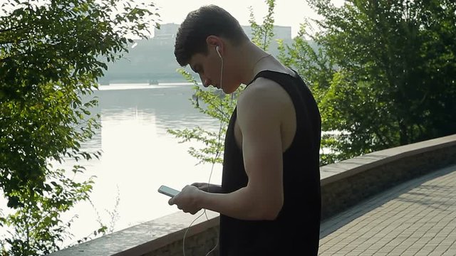 A male runner who trains and trains on a healthy lifestyle in the park stopped and talks on the phone