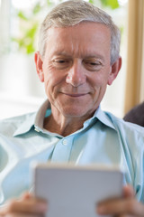 Mature Man Using Digital Tablet At Home