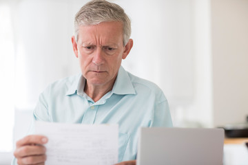 Fototapeta premium Worried Mature Man With Laptop Calculating Household Finances