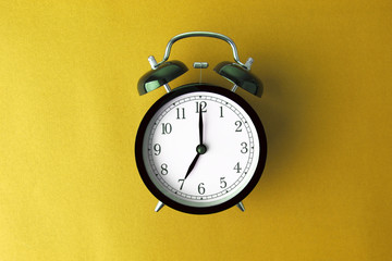 vintage black alarm clock on yellow color background