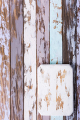 Rustic white chopping board on multicolored old wooden plank background. Copy space.