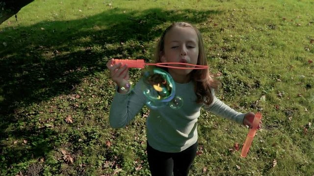 Cute curly girl is playing with soap Bubbles