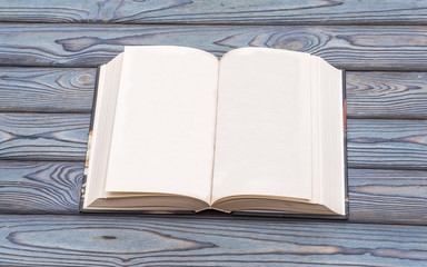 Vintage book, open, blank pages, on blue wooden table.