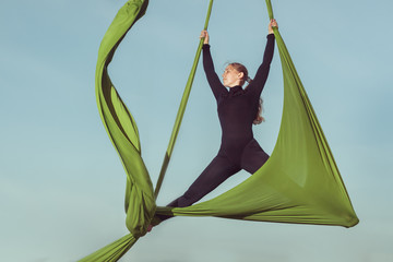 Sporting tricks on a hammock, woman aerial acrobat.