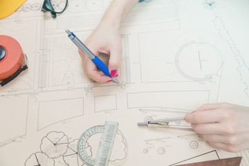Architect drawing on a blueprint with a compass and ruler.