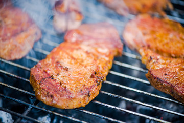 Pieces of meat grilling on hot BBQ grid