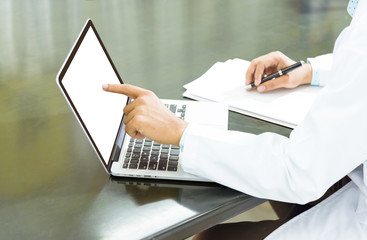 Portrait of a professional male doctor using his laptop computer in office with copy space on computer,Health care and Technology concept.