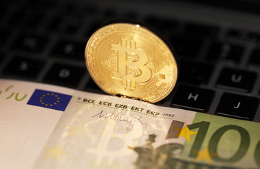 Single bitcoin coin or icon standing in sharp focus on a reflective surface