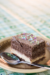 Colorful sprinkles on the chocolate cake served on the plate with spoon