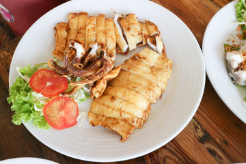 grilled squid on white dish and wood table
