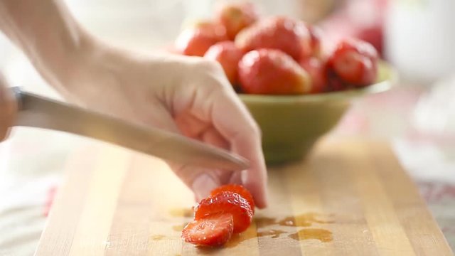 Female hands cutting fresh strawberry