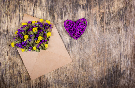 Dry wild flowers in an envelope and a wicker heart. Romantic concept. Copy space