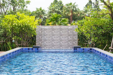 Swimming pool in backyard with fountain curtain Blue water and blue master tile