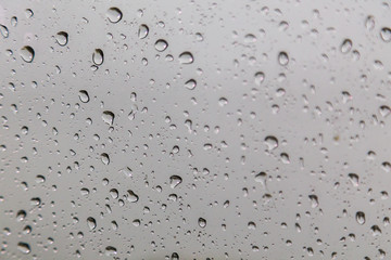 Rain drops on window glasses surface with gray sky background .Rain pattern close up of raindrops isolated on gray background.