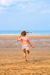 Little girl runs across the beach.