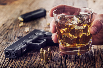 Gun and alcohol. 9mm pistol gun and cup whiskey cognac or brandy