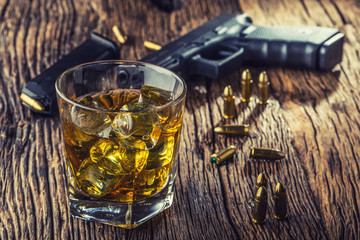 Gun and alcohol. 9mm pistol gun and cup whiskey cognac or brandy