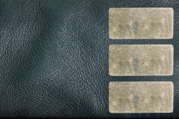 Texture of a leather jacket with three small rectangular metal label for your text. The texture is a close-up macro shot.