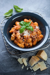 Potato gnocchi with meat sauce, parmesan cheese and fresh green basil, vertical shot