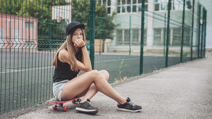Fototapeta na wymiar Beautiful young woman with skateboard posing outdoors