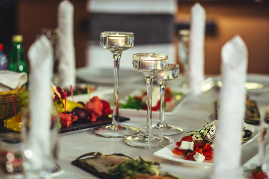 Preparation for the banquet. Served table. Lighted candles, fruits and salads.