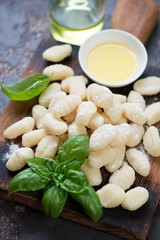 Close-up of uncooked potato gnocchi with green basil and olive oil, selective focus, vertical shot