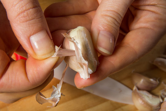 Female hands close-up, peel garlic as an ingredient for soup making.