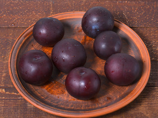 Ripe plums on a clay plate.