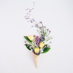 Waffle cone with lilac flower, lily of the valley, tulips bouquet on background. Flat lay, top view floral background.