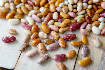Pinto beans on wooden background. Different colors of dried pinto beans.