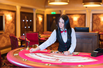 Cute lady casino dealer at poker table.