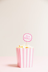 It's a girl sign in a popcorn bag at the baby shower party.  Empty background.  Baby shower celebration concept