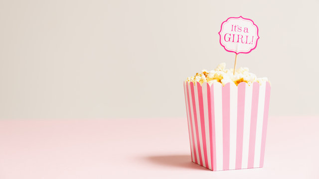 It's a girl sign in a popcorn bag at the baby shower party.  Empty background.  Baby shower celebration concept