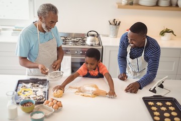Boy preparing cookie dough with his father and grandfather in