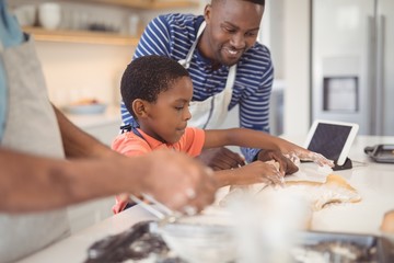 Boy preparing cookie dough with his father and grandfather in